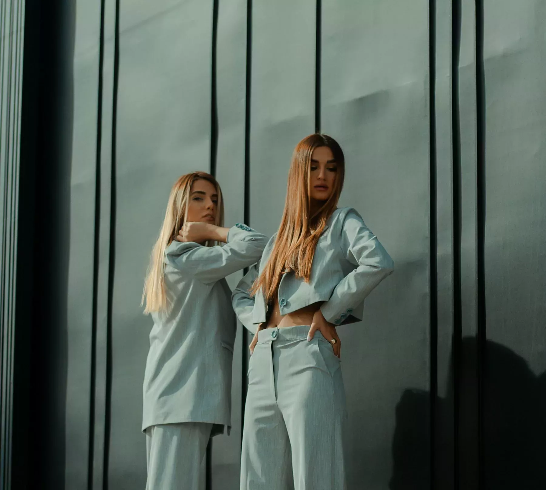 2 women in white long sleeve shirt standing beside glass window